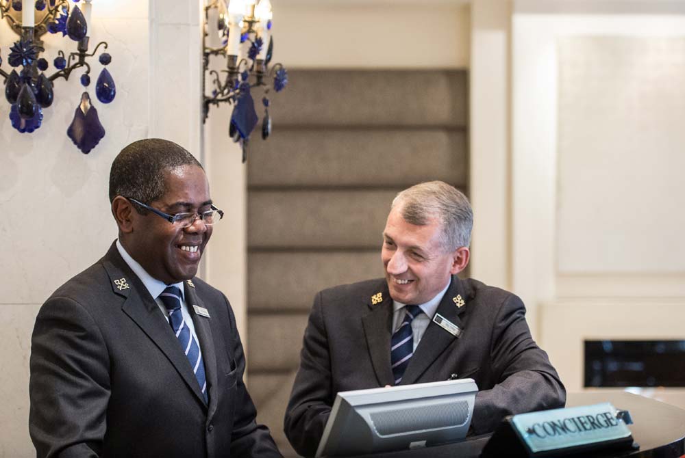 Two smartly dressed concierges working at the concierge desk