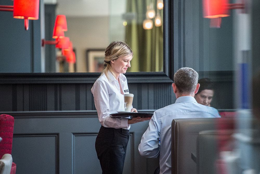 Waitress bringing coffee over to guests